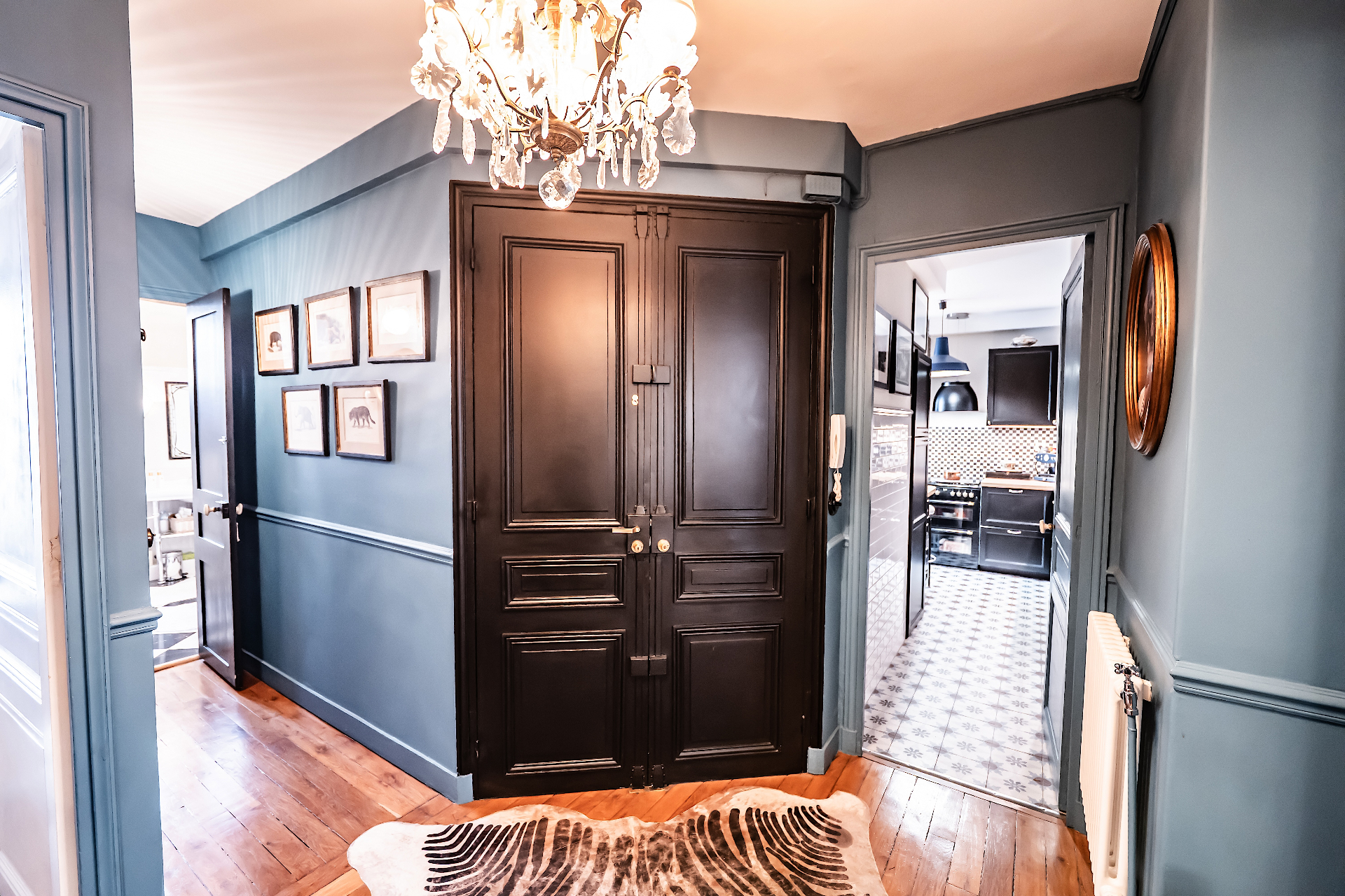 Entrée bleue avec double porte noire et lustre